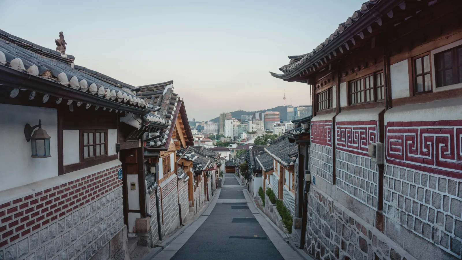 首尔韩屋街巷两侧的瓦屋檐，远处可见南山首尔塔